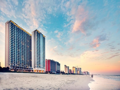 Exterior shot of Ocean 22 by Hilton Grand Vacations with cotton candy sunset skies overhead, Myrtle Beach. 