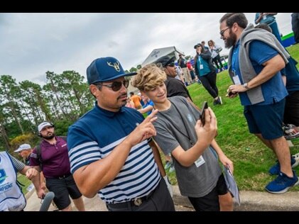 Celebrity snapping a selfie with a young spectator at Hilton Grand Vacations Tournament of Champions.