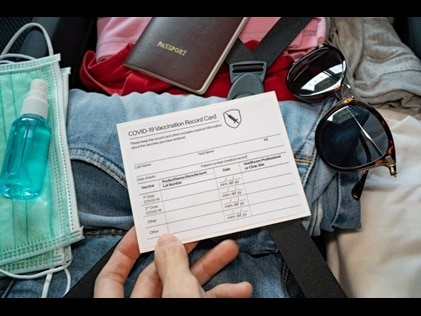 Close up of vaccine card and other travel-related items. 
