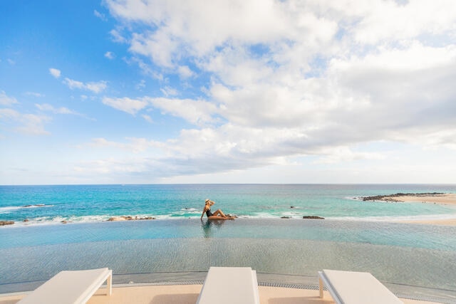 Woman sitting on the edge of an infinity pool at La Pacifica Los Cabos by Hilton Club in Mexico. 