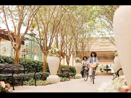 Two women riding bikes and smiling at Parc Soleil by Hilton Grand Vacations, Orlando, Florida. 