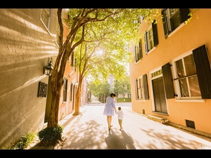 Woman and child walking down historic Charleston, South Carolina, street holding hands. 