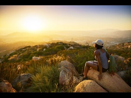 Woman hiker stopping to enjoy the sunrise view, Carlsbad, California. 