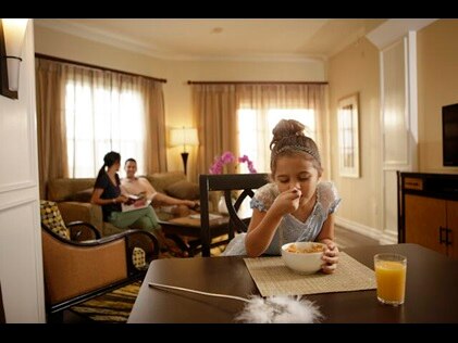 Young girl wearing a princess costume eating breakfast with family in their in-suite kitchen at SeaWorld® Orlando, a Hilton Grand Vacations Club, Orlando, Florida. 