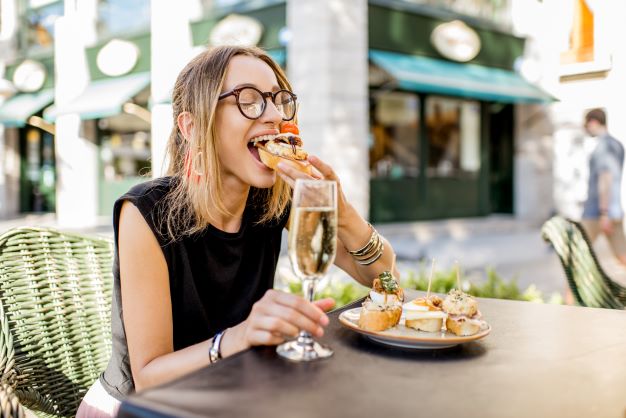 Woman tasting tapas-style small plates with champagne. 