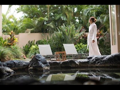 Woman standing in white spa robe at Kohala Spa, Hilton Waikoloa Village, Hawaii. 