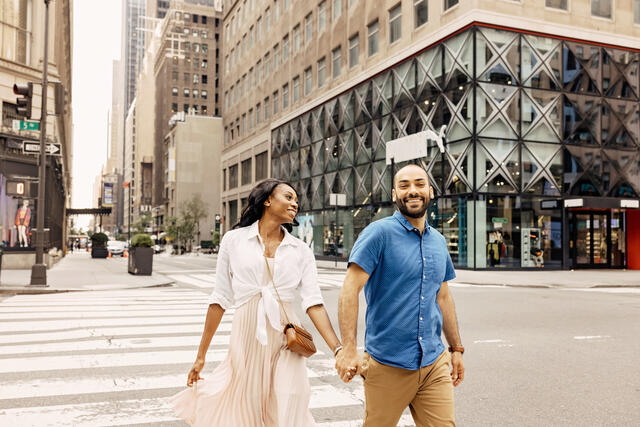 Couple holding hands and walking happily across a New York City street, New York.