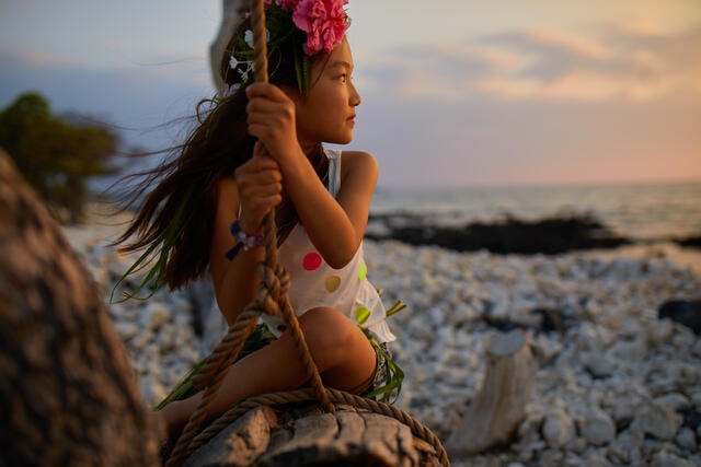 Young girl gazing out to the Pacific Ocean with the glow of sunset on her face, Big Island, Hawaii. 