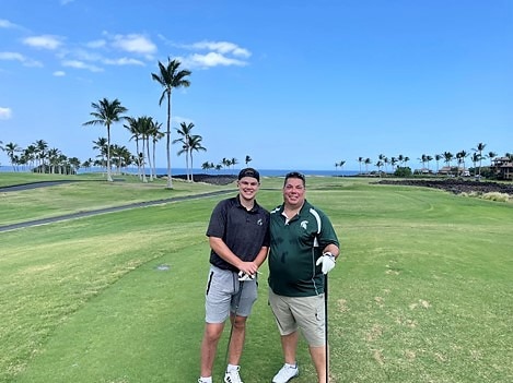 Hilton Grand Vacations Owner and son posing on golf course during Hawaiian vacation. 