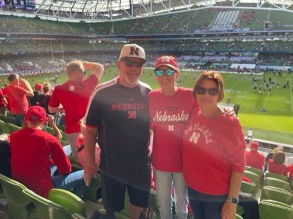 Hilton Grand Vacations Owner Erin W. and her family at an American football game, wearing red Nebraska Huskers shirts, at Aviva Stadium in Dublin, Ireland