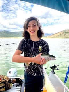 Zev, grandson of Hilton Grand Vacations Owner Bruce, holding a fish while fishing in Brian Head, Utah