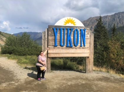 Hilton Grand Vacations Owner Rania poses by a sign for Yukon in Alaska 