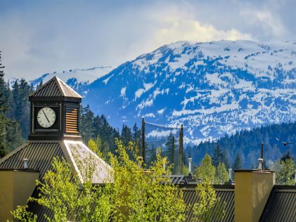 Clock tower in Whistler Village in Whistler, Canada, with snowy mountains in the background