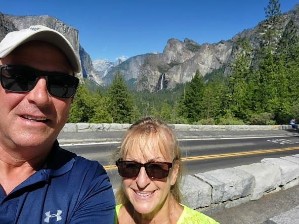 Hilton Grand Vacations Owners snapping roadside-selfie, mountains, waterfall in distance. 