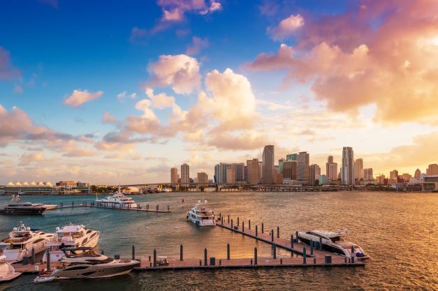 Beautiful aerial, yacht-lined dock, sunset sky overhead Miami skyline, Florida. 