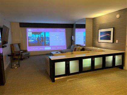 Living room and projector screen with a welcome message at Elara, a Hilton Grand Vacations Club, in Las Vegas