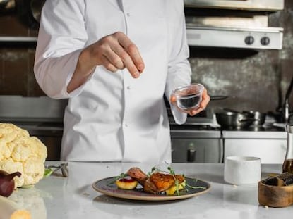 A chef sprinkles a final garnish on a dish