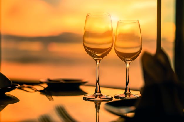 Two wine glasses on a table during a romantic dinner at sunset