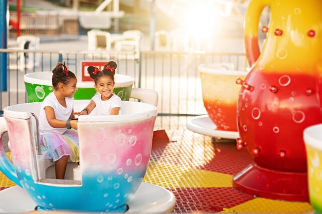 Two cute young girls having fun on a tea cup ride at Orlando theme park, Florida.