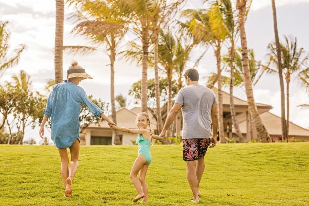 Family of three walking hand in hand, small girl looking back, Maui Bay Villas, a Hilton Grand Vacations Club, Hawaii. 