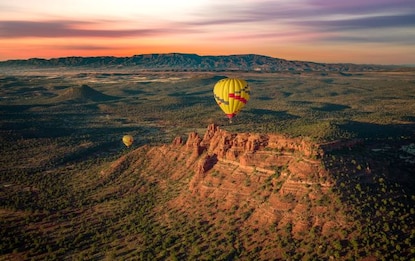 Hot air balloons floating gracefully above Arizona's Red Rocks, with purple and pink painted skies, Sedona. 