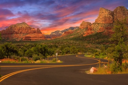 Wide open road winding through the Arizona desert with cotton candy sunset skies overhead, Sedona. 