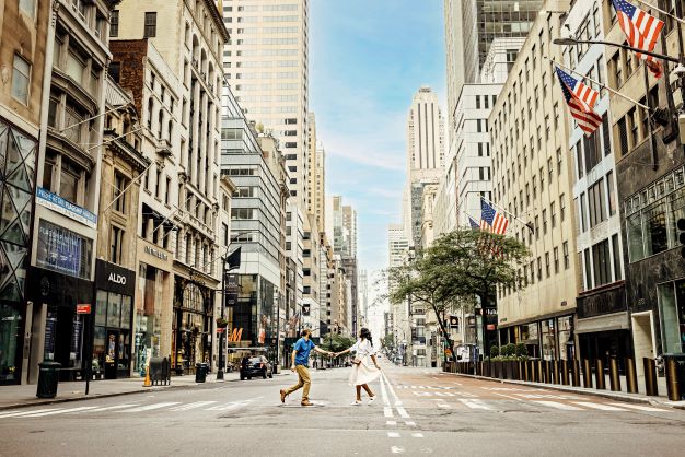 A man and woman holding hands and crossing a street in New York, New York