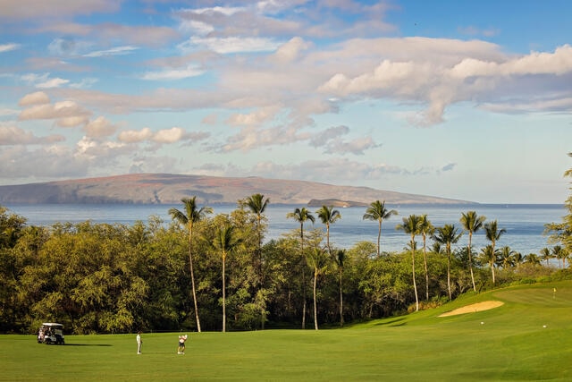 Stunning aerial image of golfers on a picturesque course, ocean and mountains in the distance, Maui, Hawaii. 