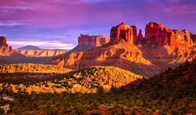 A picture of the Arizona desert near Sedona at sunset, a purple, cloudy sky behind red mesas and desert landscape