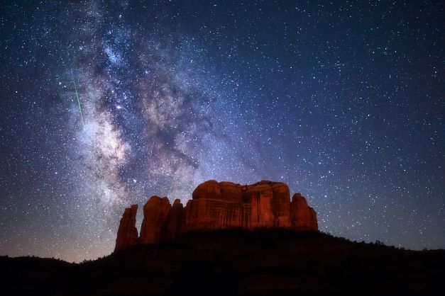 A red rock mesa in the Arizona desert at night, with a backdrop of a star-filled sky