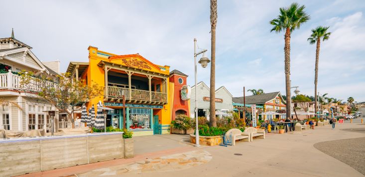 Idyllic beachside retail shops, palm trees in the distance, Front Street, Avila Beach, California.