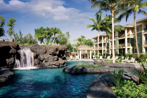 The view of the pool at Kings' Land, a Hilton Grand Vacations Club, on Hawaii's Big Island, with palm trees and suites in the background