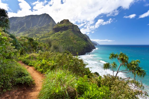 A view from Kauai, Hawaii, with lush, forested mountains on the left, and crystal-blue waters to the right
