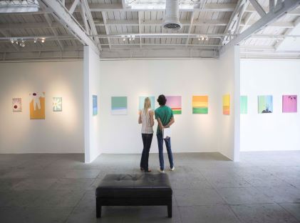 A couple looks at art on the wall of an art gallery