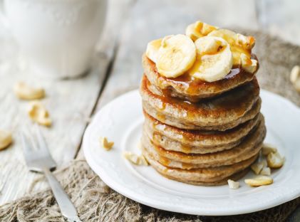 A stack of pancakes topped with bananas for breakfast