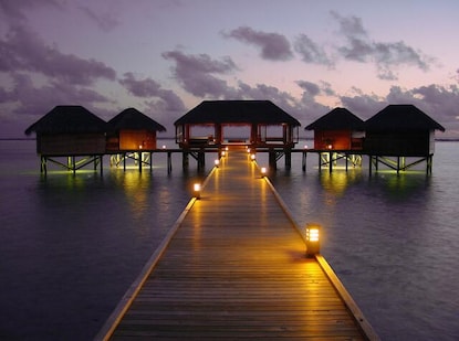 Idyllic tropical scene, overwater bungalows glowing against the dusk sky, Conrad Maldives Rangali Island. 
