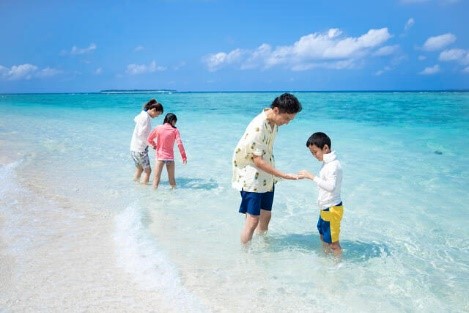 Family frolicking in bright blue waters, bright blue sky, Okinawa, Japan. 