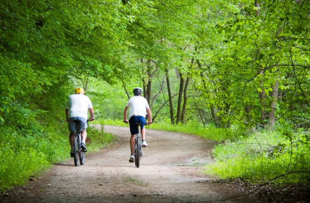 Two men riding bicycles along tree-lined dirt path, Gatlinburg, Tennessee. 