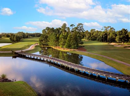 Two people walk on a boardwalk across a water hazard at a golf course in Orlando, Florida