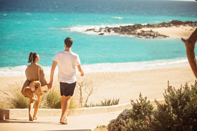 Couple walking hand in hand beachside, La Pacifica Los Cabos, a Hilton Club, Mexico. 