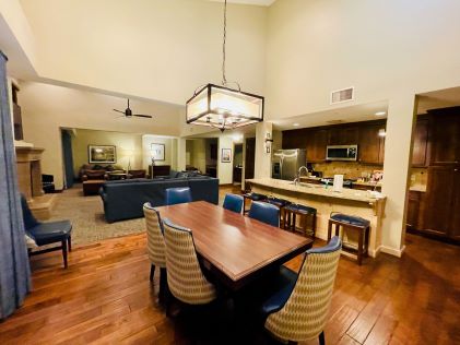 The kitchen and living area of a 3-Bedroom Suite at Sunrise Lodge, a Hilton Grand Vacations Club, in Park City, Utah, complete with a dining table, sofas, a fireplace and fully stocked kitchen