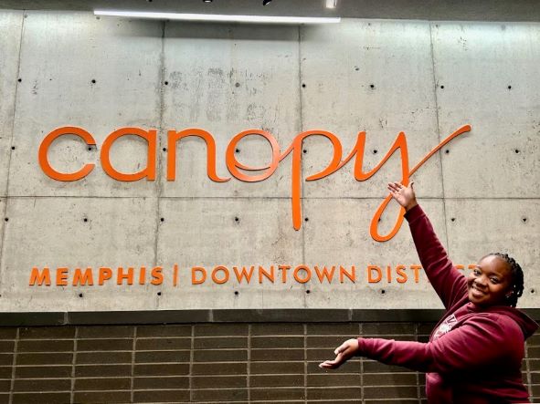 A Hilton Grand Vacations Owner poses in front of the sign of Canopy by Hilton Memphis Downtown Beale Street