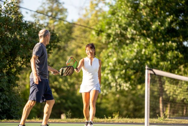 Couple happily playing pickleball outdoors. 