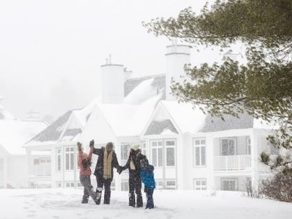 A family playing in the snow at Tremblant, a Hilton Grand Vacations Club in Quebec, Canada