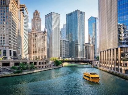 A yellow tour boat on the river in downtown Chicago, surrounded by skyscrapers