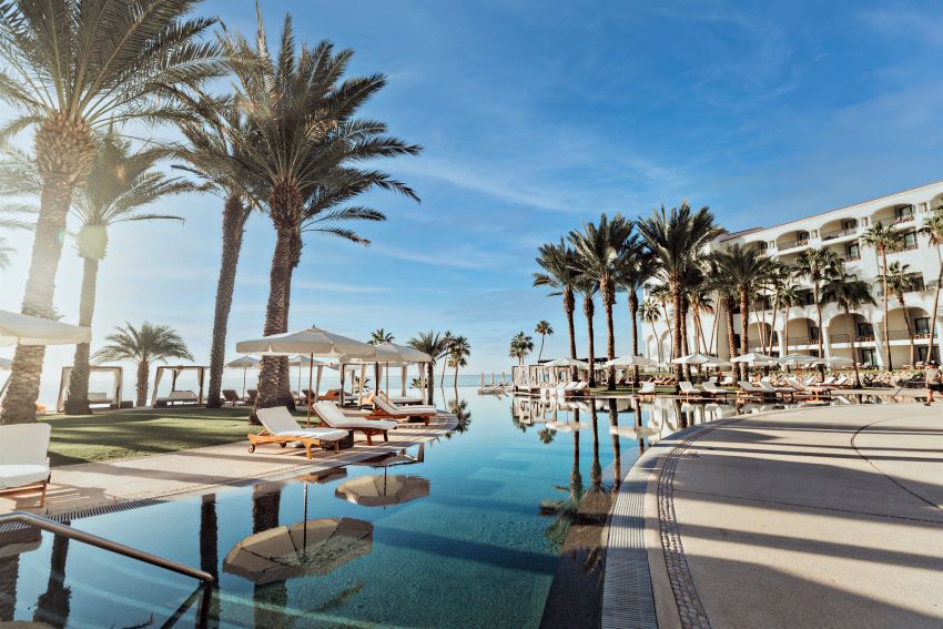 The pool at La Pacific Los Cabos, a Hilton Club in Mexico, surrounded by palm trees and lounge chairs