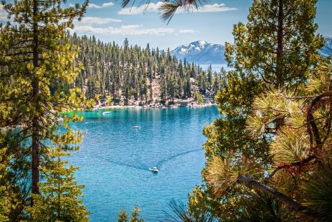 Alpine view, boat cutting through emerald waters, Lake Tahoe, California.