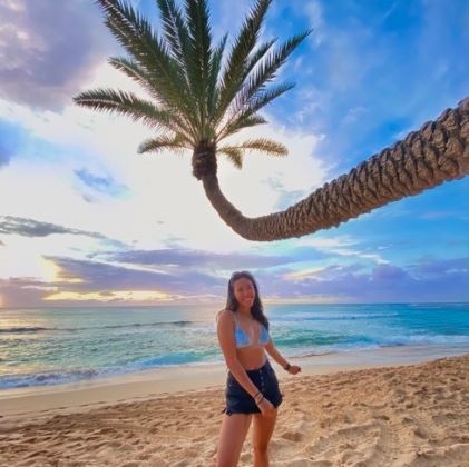 A Hilton Grand Vacations Owner poses on the beach of Oahu at sunset