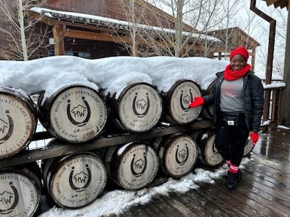 A Hilton Grand Vacations poses by barrels as part of a distillery tour in Park City, Utah