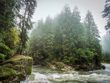 Two hikers by a river in the forest north of Vancouver